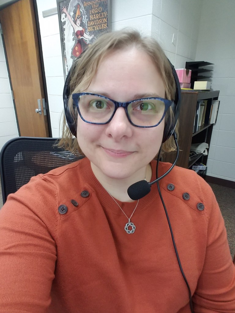 Photo of archivist Jennifer Motszko seated in an office chair with her headset on.